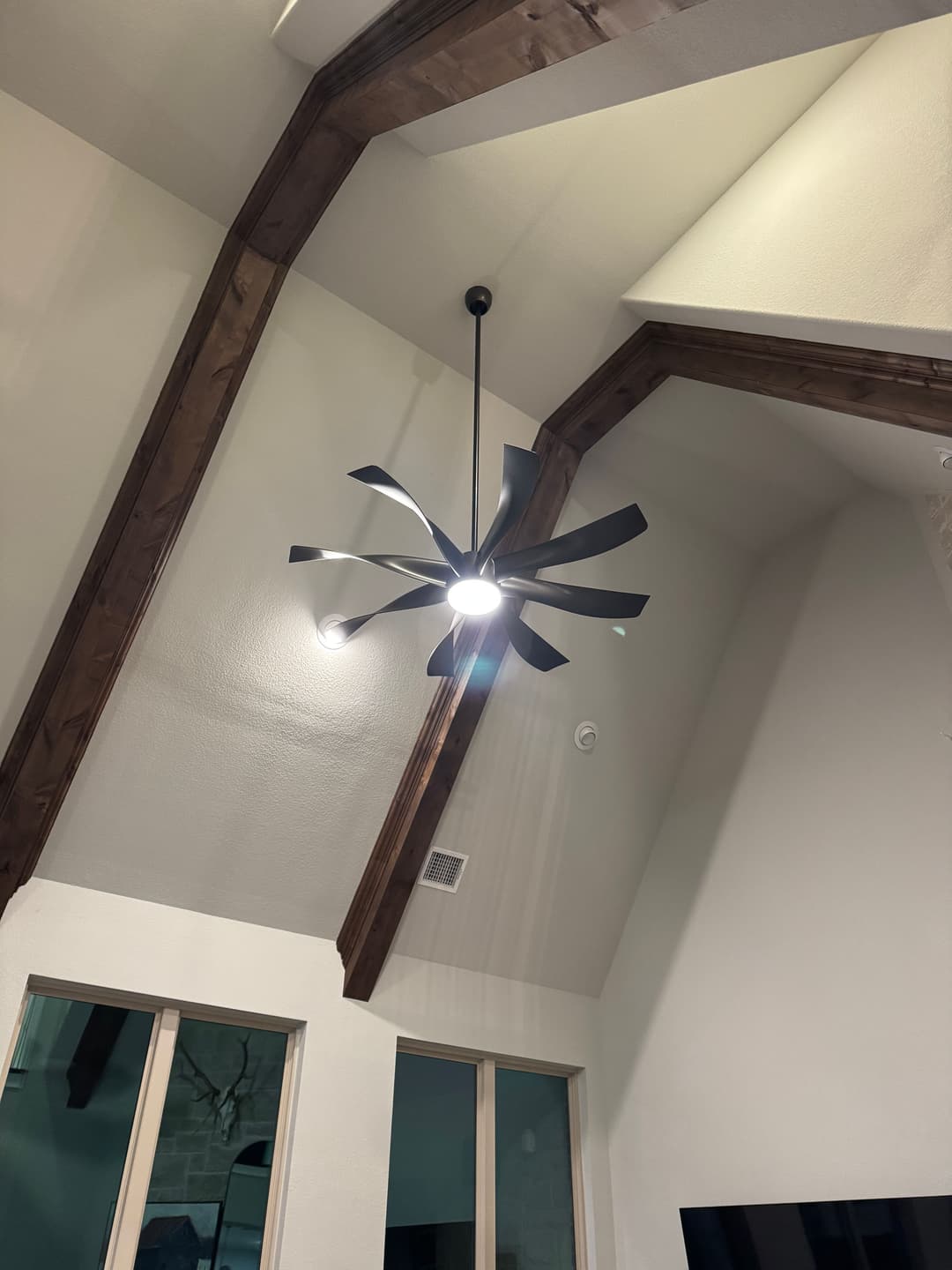 Modern black ceiling fan with stylish blades in a high, vaulted ceiling living room.