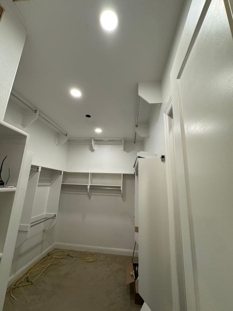Spacious unfinished closet with white walls, recessed lighting, and shelving units.