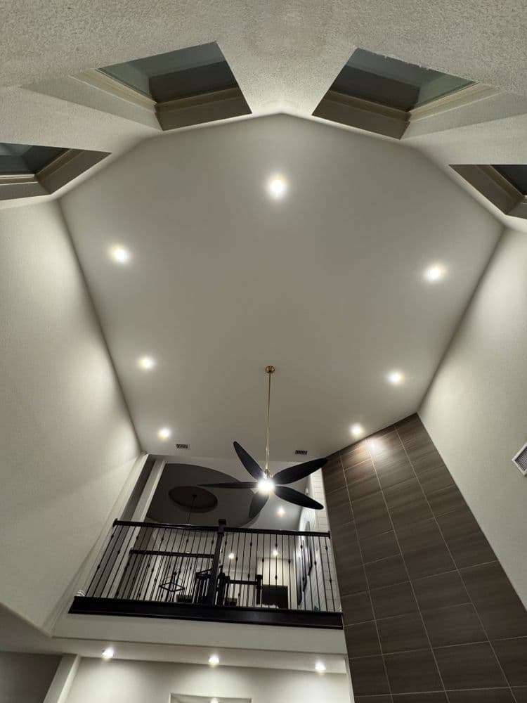 Modern interior with high octagonal ceiling, sleek fan, and stylish railing.