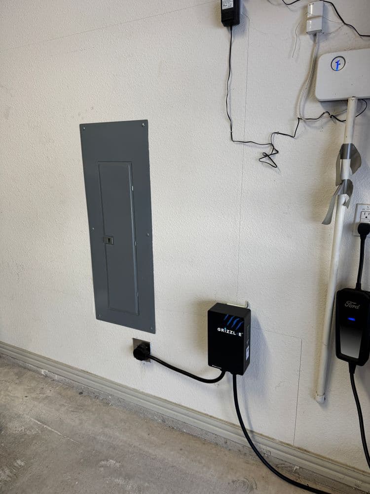 Electrical panel and EV charger installed on a garage wall. Efficient power management solution.