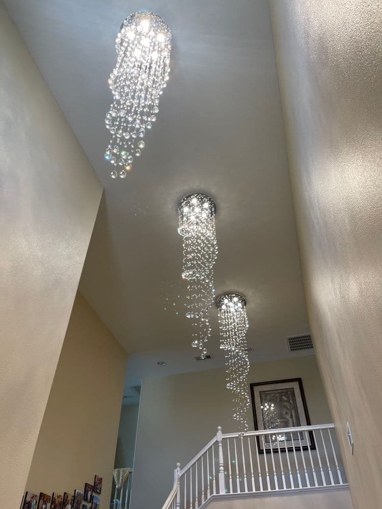Chic modern chandeliers with crystal beads illuminate a stylish hallway staircase.