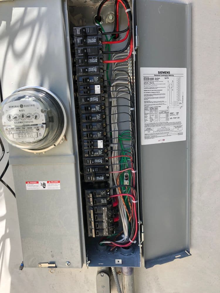 Siemens electrical panel with circuit breakers and meter, showcasing wiring details.