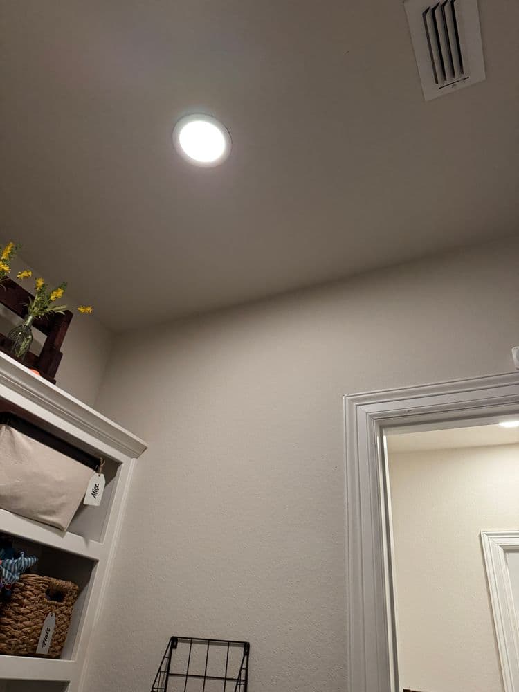 Bright ceiling light in organized storage area with baskets and a wall vent.