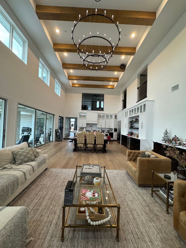 Spacious modern living room with high ceilings, elegant chandelier, and stylish furniture.