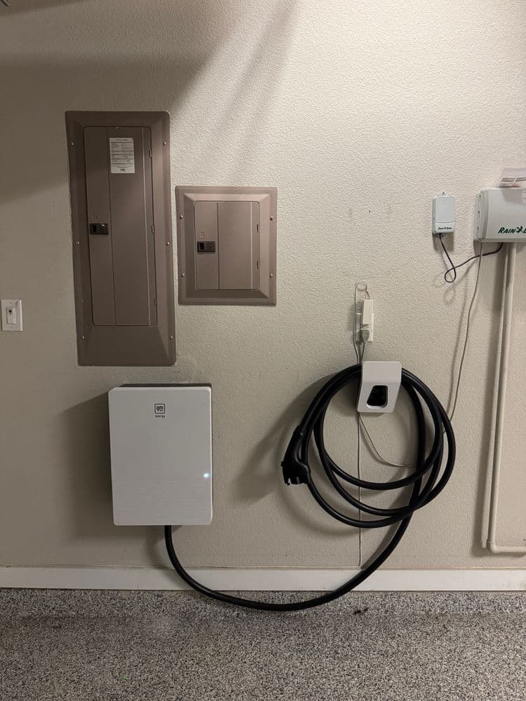Electric vehicle charging station with wall-mounted charger and power panels in garage.
