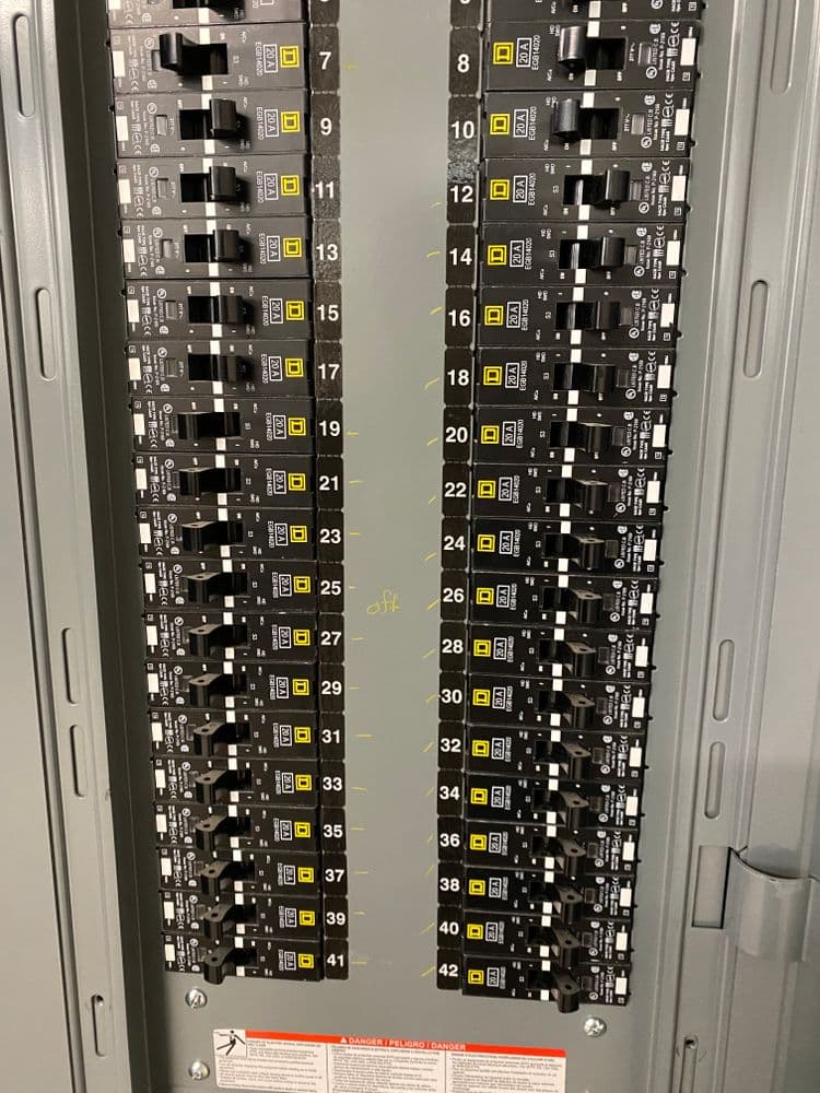 Electrical circuit breaker panel with labeled switches and safety warning at the bottom.