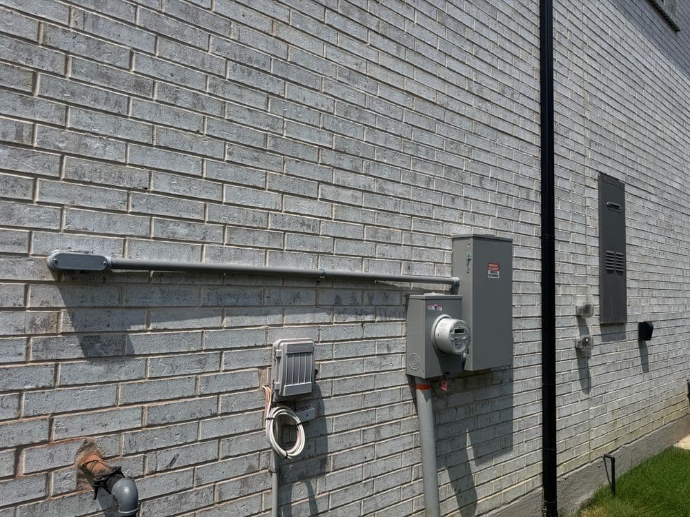 Electrical meter and conduit installed on a gray brick wall, showcasing utility connections.