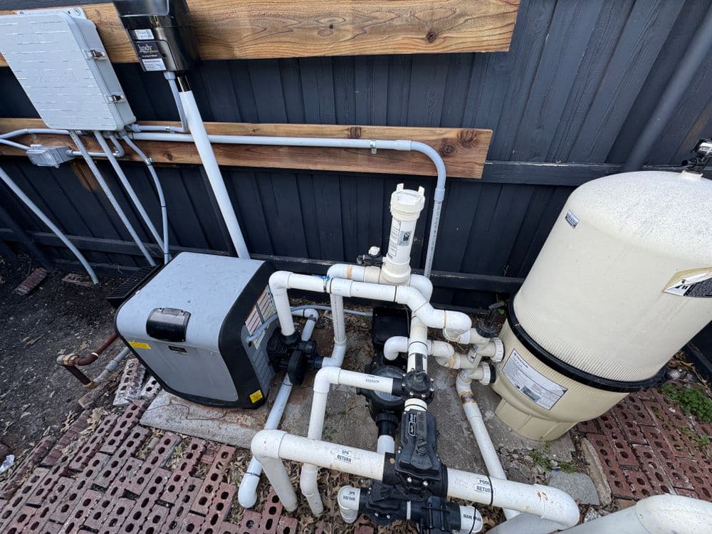 Residential plumbing system with pump and tank, surrounded by PVC piping.